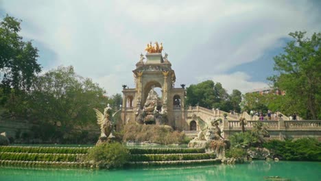 Atemberaubendes-Video-Eines-Mädchens-In-Grünem-Kleid-Und-Strickmütze,-Das-Die-Cascada-Monumental-Im-Parc-De-La-Ciutadella,-Barcelona,-Spanien,-Beobachtet