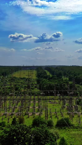 high voltage line among fields. electric supports against the sky among green nature. power transmission lines in summer. aerial view. vertical video