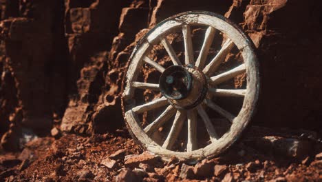 old wooden cart wheel on stone rocks