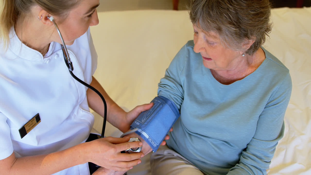 Doctor checking senior woman blood pressure on bed 4k