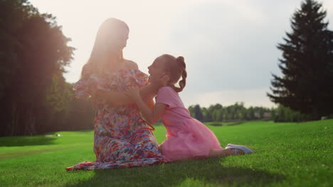 Family-spending-time-in-city-park.-Girl-pushing-woman-on-grass-in-meadow.
