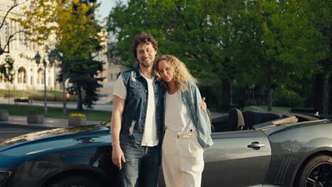 una linda pareja amorosa de un chico y una chica en chaquetas de vaqueros están de pie posando y mirando a la cámara contra el fondo