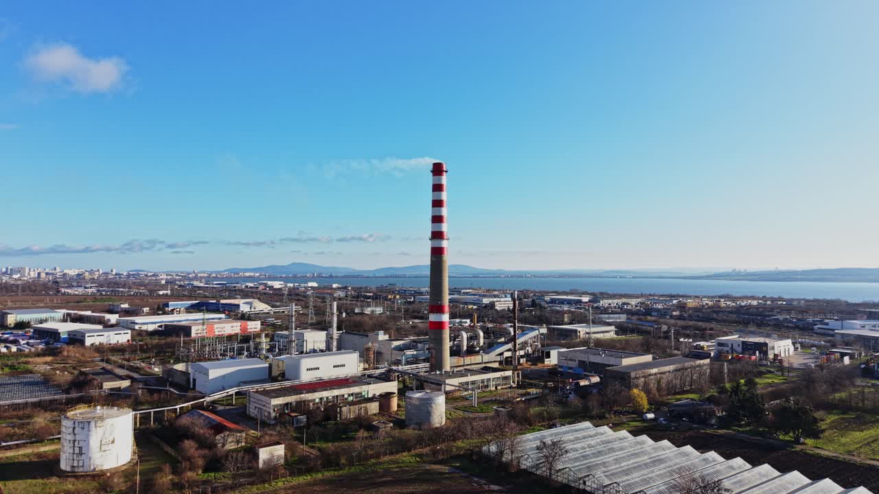 Scenen viser et industriområde med en høy skorstein