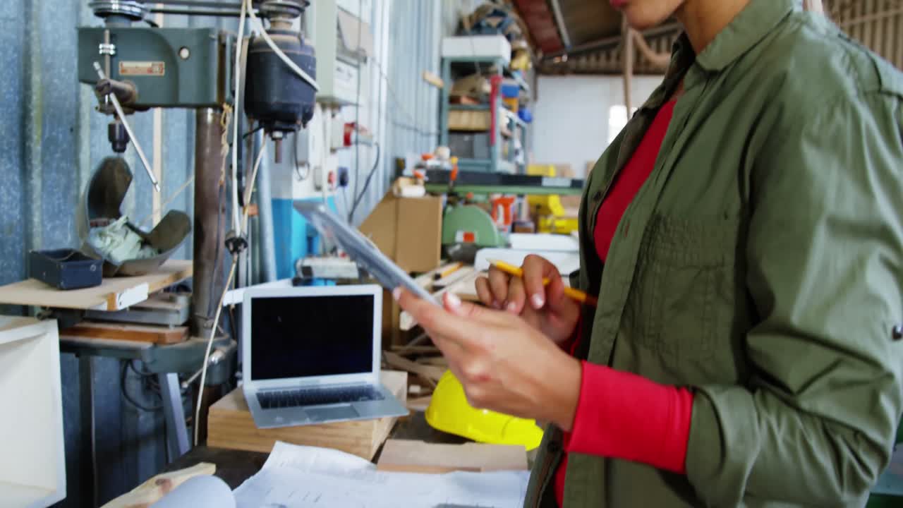 carpintero atractivo trabajando en su tableta y sonriendo a la cámara