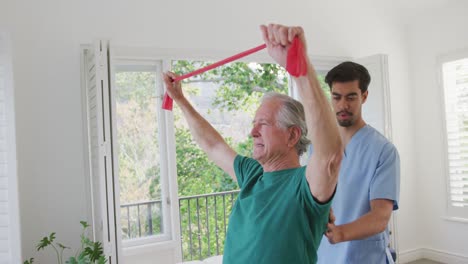 Slow-motion-of-senior-man-exercising-with-resistance-band-by-male-physiotherapist-at-retirement-home