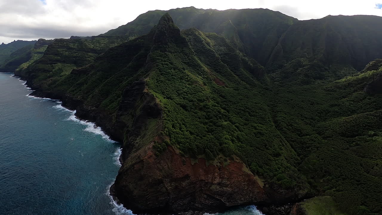 vista aérea de la costa azul y las olas rompiendo a lo largo de las colinas ondulantes en kauai hawaii