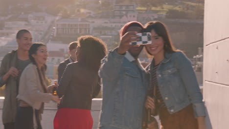 happy group of friends posing for selfie photo enjoying summer rooftop party celebration having fun dancing together sharing weekend on social media