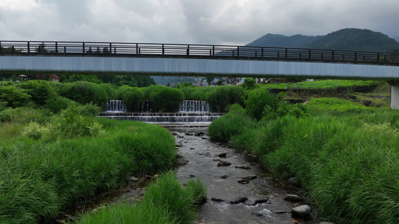 일본 야마노치의 카쿠마 강에 있는 작은 폭포 위를 기울이는 드론 촬영