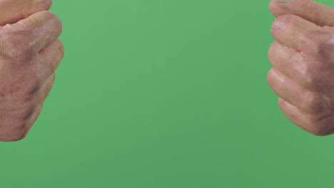 dos puños de yeso pintados de manera realista se rompen entre sí en pedazos en la pantalla verde