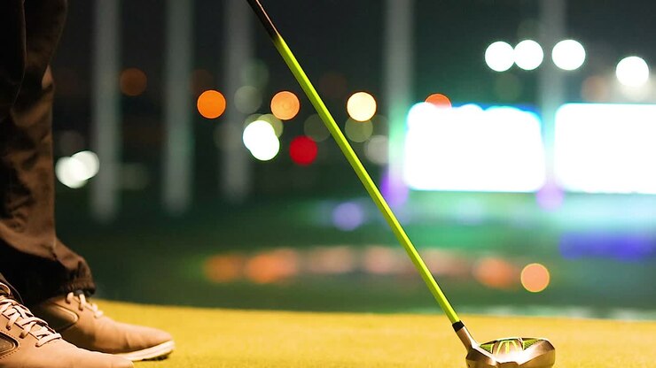 Scarpe e mazza da golf di un golfista posizionate su un campo pratica illuminato di notte