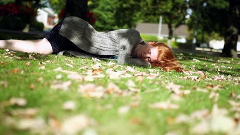 Peaceful napping redhead lying on green lawn
