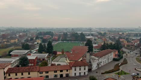drone footage descending on soccer players actively playing on a field near bergamo, italy, during a gloomy autumn day