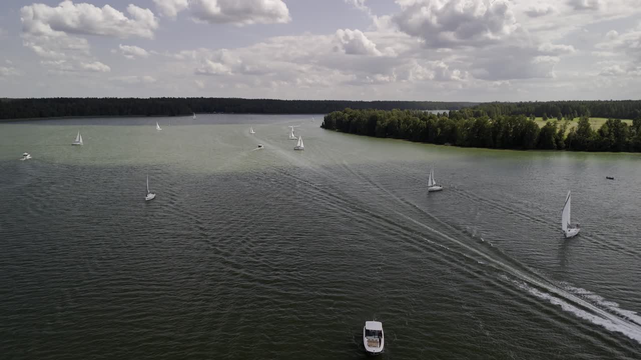 Drone view of sailing boats cruising on the lake on shallow water in summer cloudy day