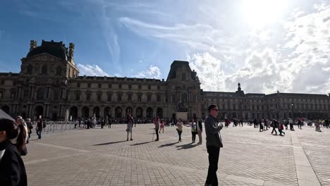 people exploring louvre courtyard on a sunny day