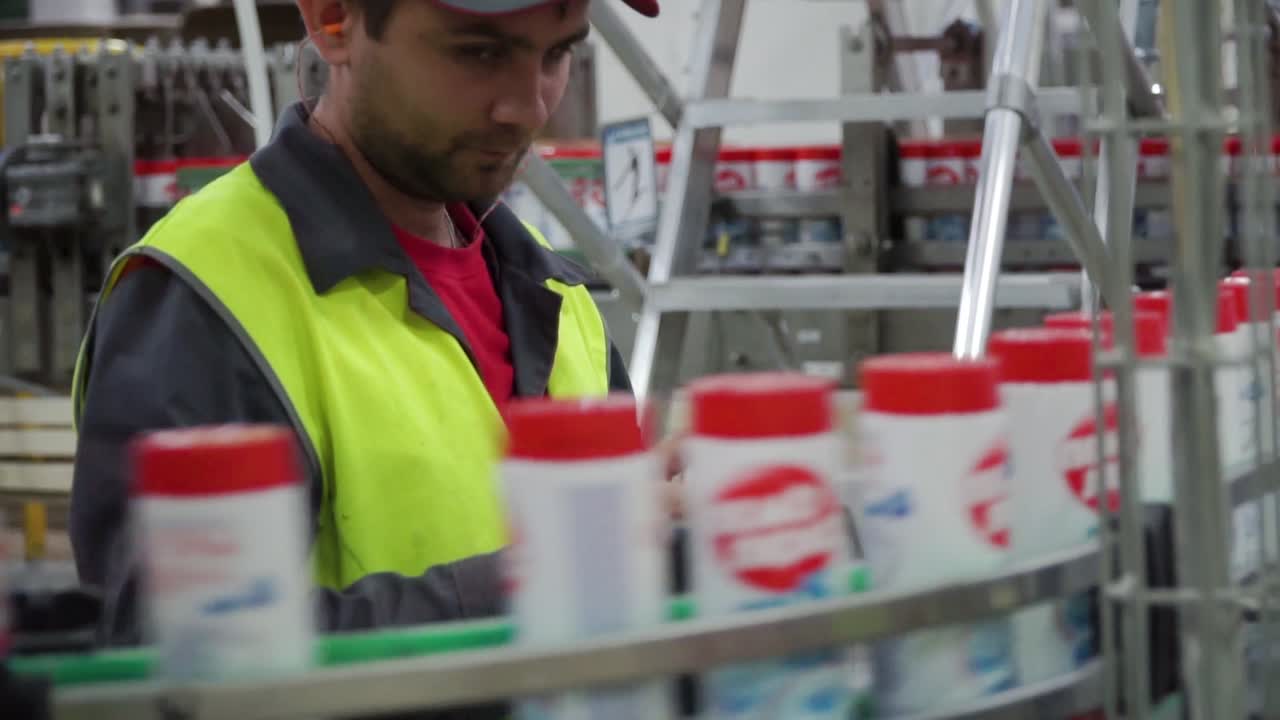 Factory worker checking and packing cleaning supplies on an assembly line