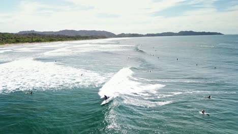 toma aérea de mucha gente surfeando en la playa de nosara en costa rica durante un día soleado en cámara lenta