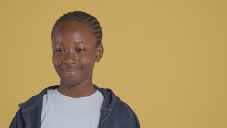 studio portrait of young boy smiling against yellow background