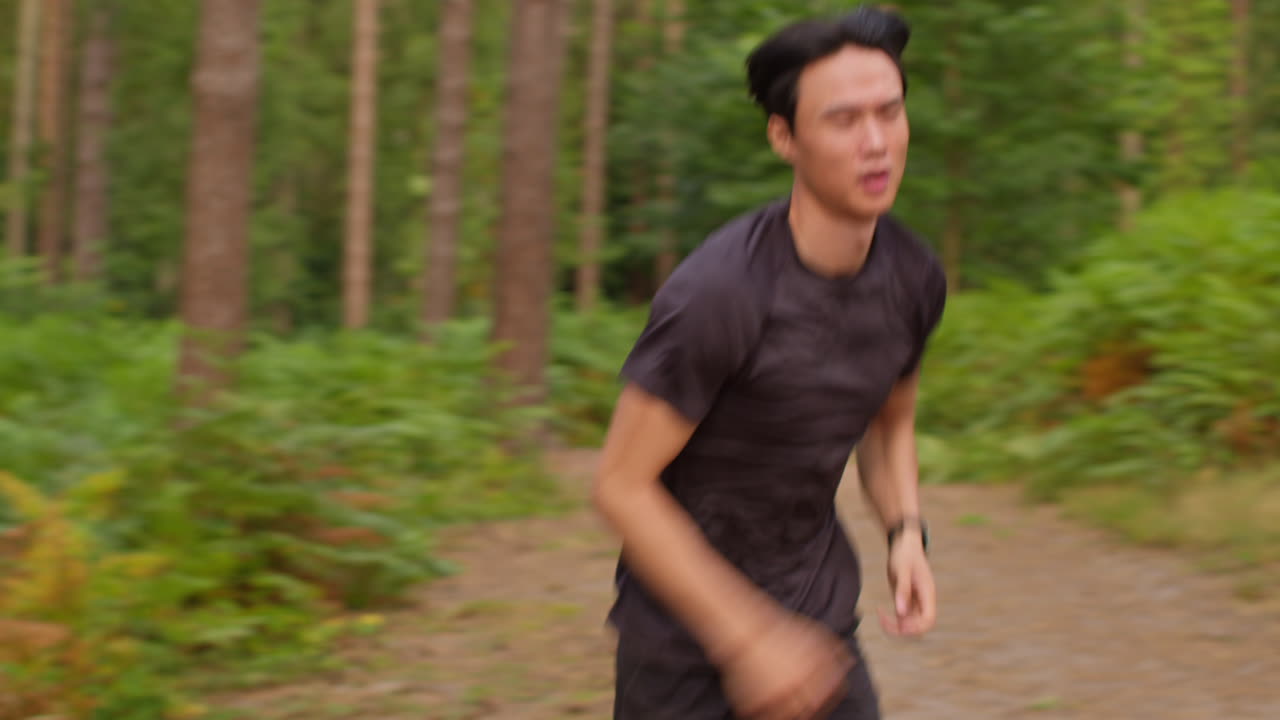 hombre adulto medio cansado haciendo ejercicio haciendo ejercicio al aire libre corriendo por una pista en el bosque deteniéndose para respirar y comprobando la actividad aplicación en reloj inteligente disparado en tiempo real