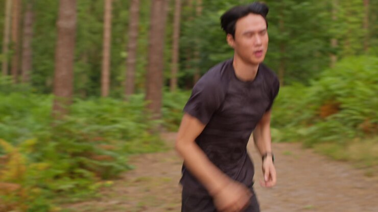 Tired Mid Adult Man Exercising Doing Work Out Outdoors Running Along Track In Forest Stopping For Breath And Checking Activity App On Smart Watch Shot In Real Time