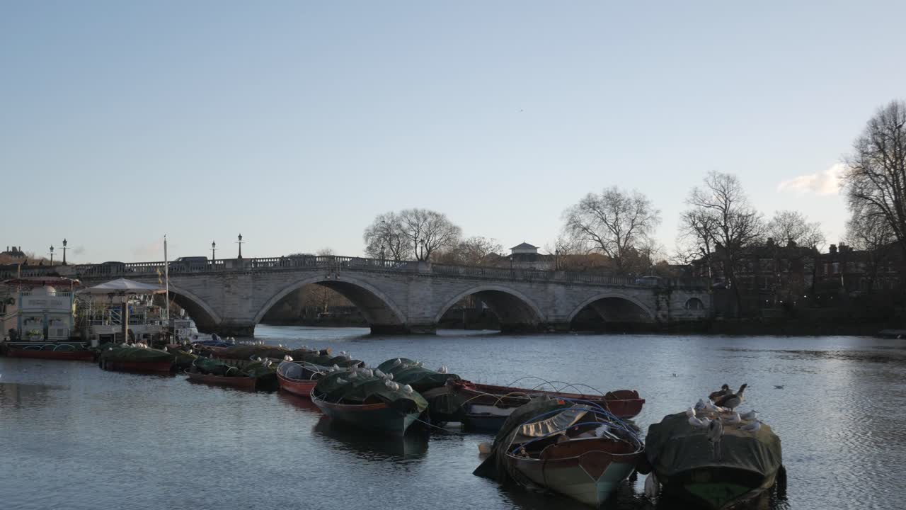 A calm riverside view of Richmond Road Bridge with boats and trees on a clear day