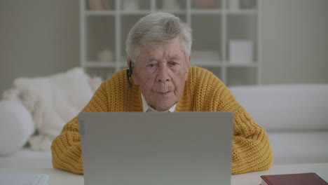 Senior-woman-with-laptop-computer-calling-on-smartphone-at-home.-Old-woman-having-a-video-call-on-the-laptop-smiling-and-talking-happily-indoors-in-a-cozy-apartment.-doctor-video-calling-older-patient