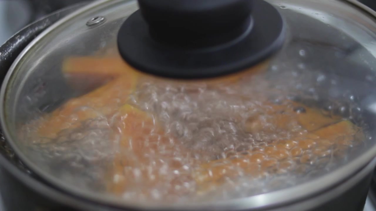 closeup pot cooking squash in boiling water with glass cover