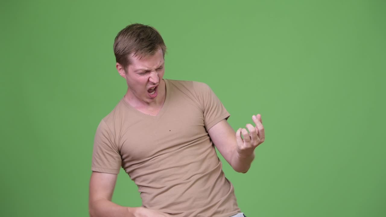 Young handsome Scandinavian man playing air guitar