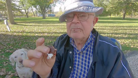 older man enjoying eating a messy smore and wiping off chocolate on his face with a white napkin