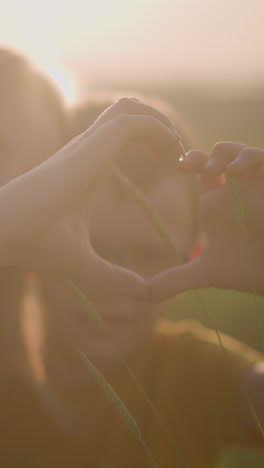 a beautifully blurred image captures the tender moment of a young boy and a woman forming a heart shape with their hands while their heads are joined together