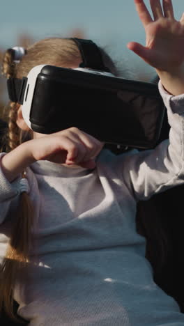 child in virtual reality glasses sits in wheelchair. girl with disability plays video game choosing digital elements with hands on blurred background closeup