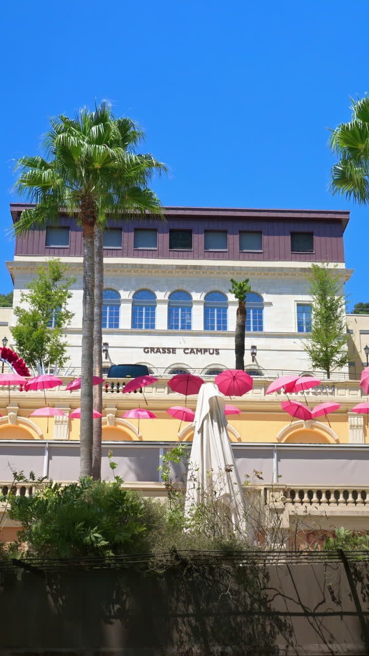 Rows of pink umbrellas above the streets of the old town in Grasse, France. Vertical