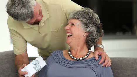 el marido le da un regalo a su esposa mientras ella está leyendo un libro