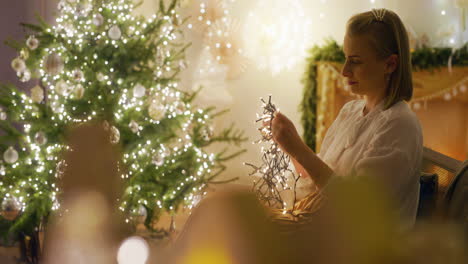 woman untangles christmas lights in warm living room