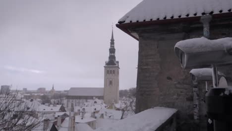 tallinn panoramic platform with view on the old town during winter with clouds and snow covering the roofs, and binoculars in foreground