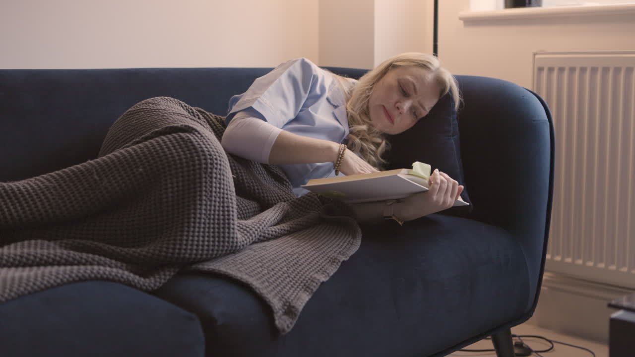 Woman sleeping on couch with book