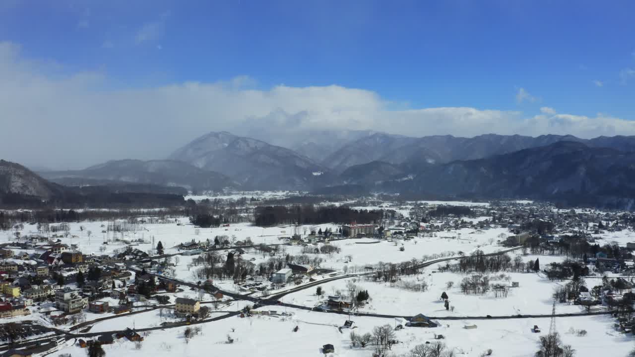 From high above, the drone's lens unveils the mesmerizing beauty of Hakuba valley and the vibrant cityscape of Hakuba, painting a stunning winter picture under the radiant sunlight of a clear day