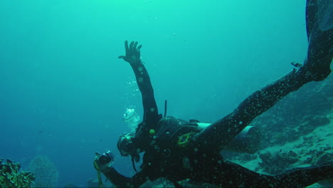 diver under water holds a camera in his hand