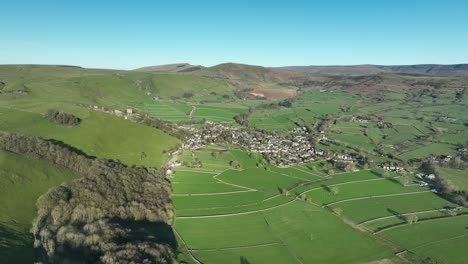 Wide-aerial-view-over-the-Peak-District-town-of-Castleton,-UK-with-Mam-Tor-and-Winnats-Pass-in-the-background