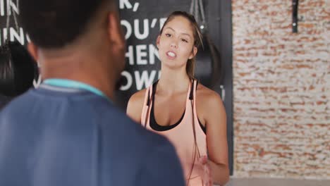 video de una mujer caucásica en forma hablando con un hombre afroamericano en el gimnasio