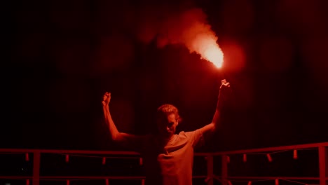 aggressive man burning signal flare on roof. football fan standing with fire