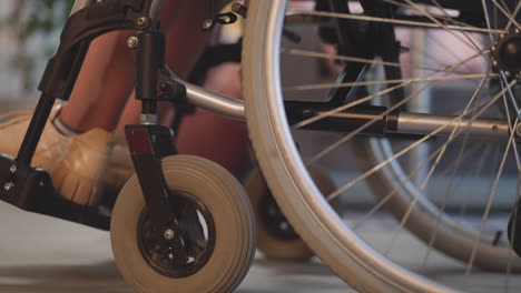 Legs-of-female-patient-with-disability-moving-in-wheelchair-in-room