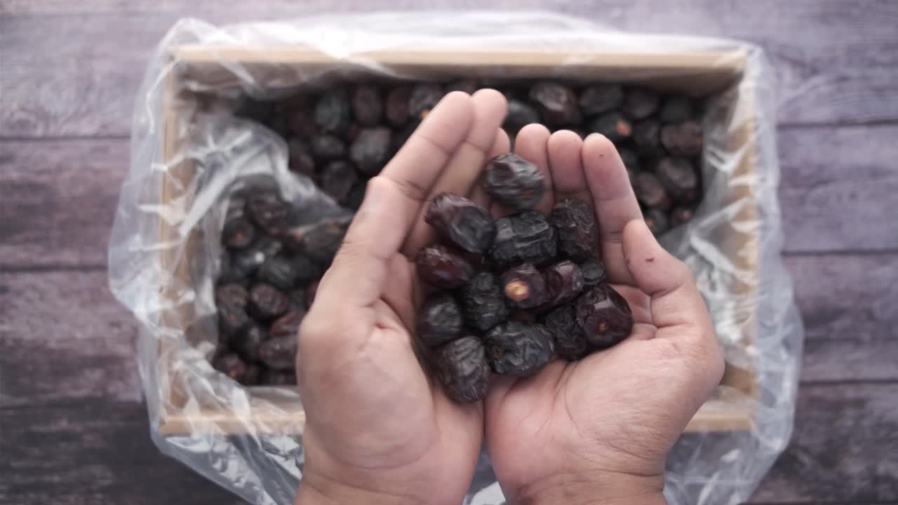 Hands holding dried dates from a box