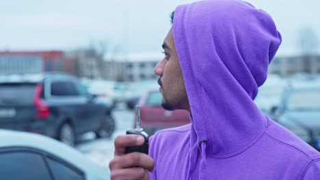 young man with a car key in his hand desperately looking for his lost car in the parking lot