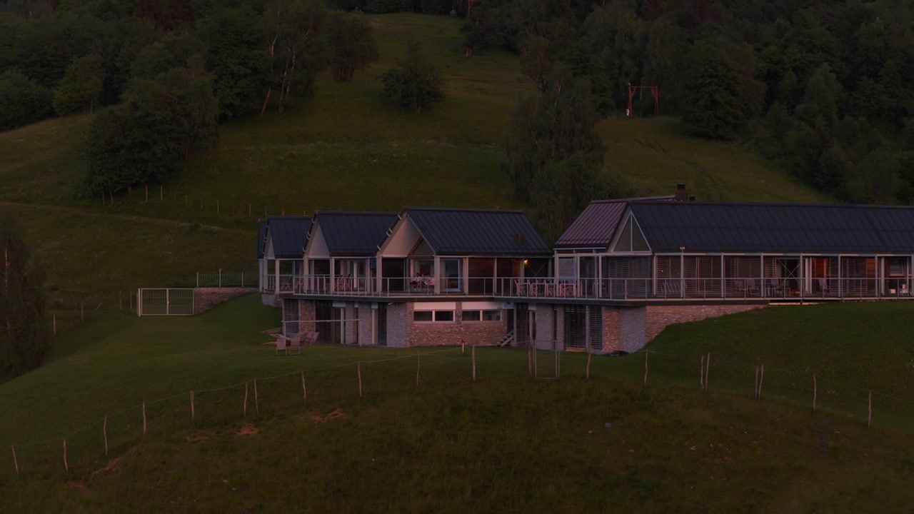 Dronebillede af ferieboliger på en bjergtop i Slovenien, der viser alpehytter omgivet af det bjergrige landskab og naturskønne omgivelser.