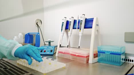 hand of medical worker checking vials of liquid. female's hand in sterile glove putting test tubes one by one into special machine in lab.