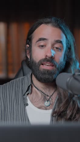 a man with a beard and long hair speaking into a microphone