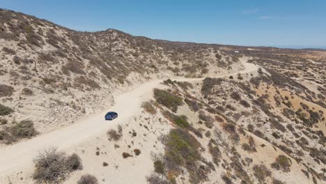 Aerial:-car-driving-on-Mexican-desert-road,-Baja-California-Sur-coastline