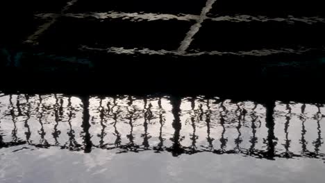 close up water surface reflection promenade steel guards, silhouette on river