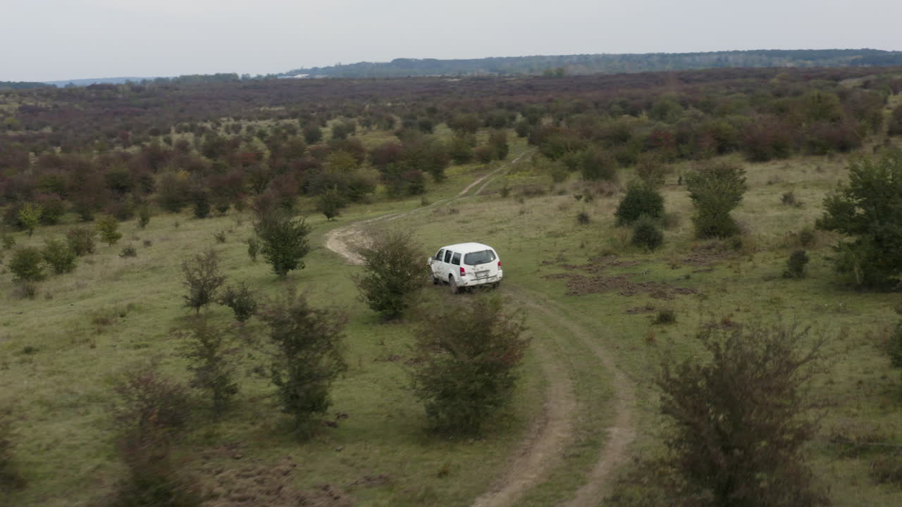 Jeep bianca che guida su una strada sterrata sconnessa di campagna, steppa cespugliosa, ripresa aerea.