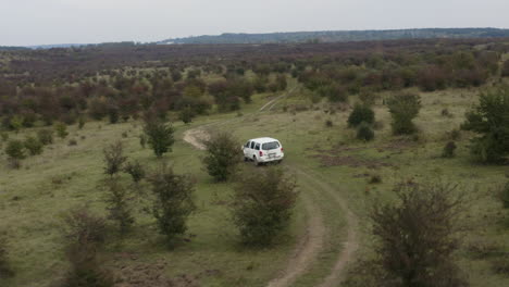 Weißer-Jeep,-Der-Auf-Einer-Holprigen-Landstraße-Fährt,-Buschige-Steppe,-Antenne